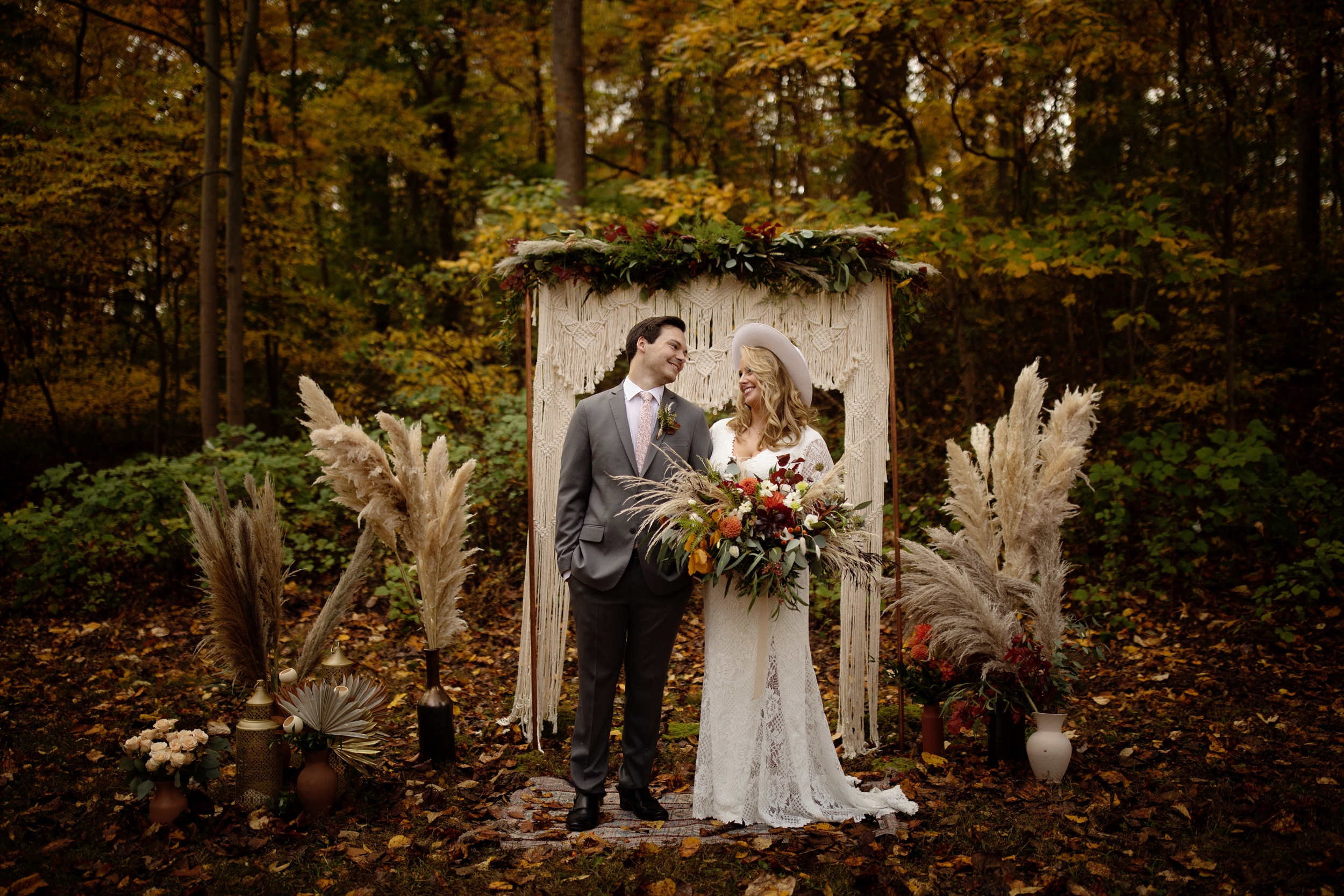 Boho Elopement at Hibernia Park in Coatsville, PA. macrame ceremony backdrop and whimsical, boho, dried florals. Bride is wearing a BHLD gown and a white hat.