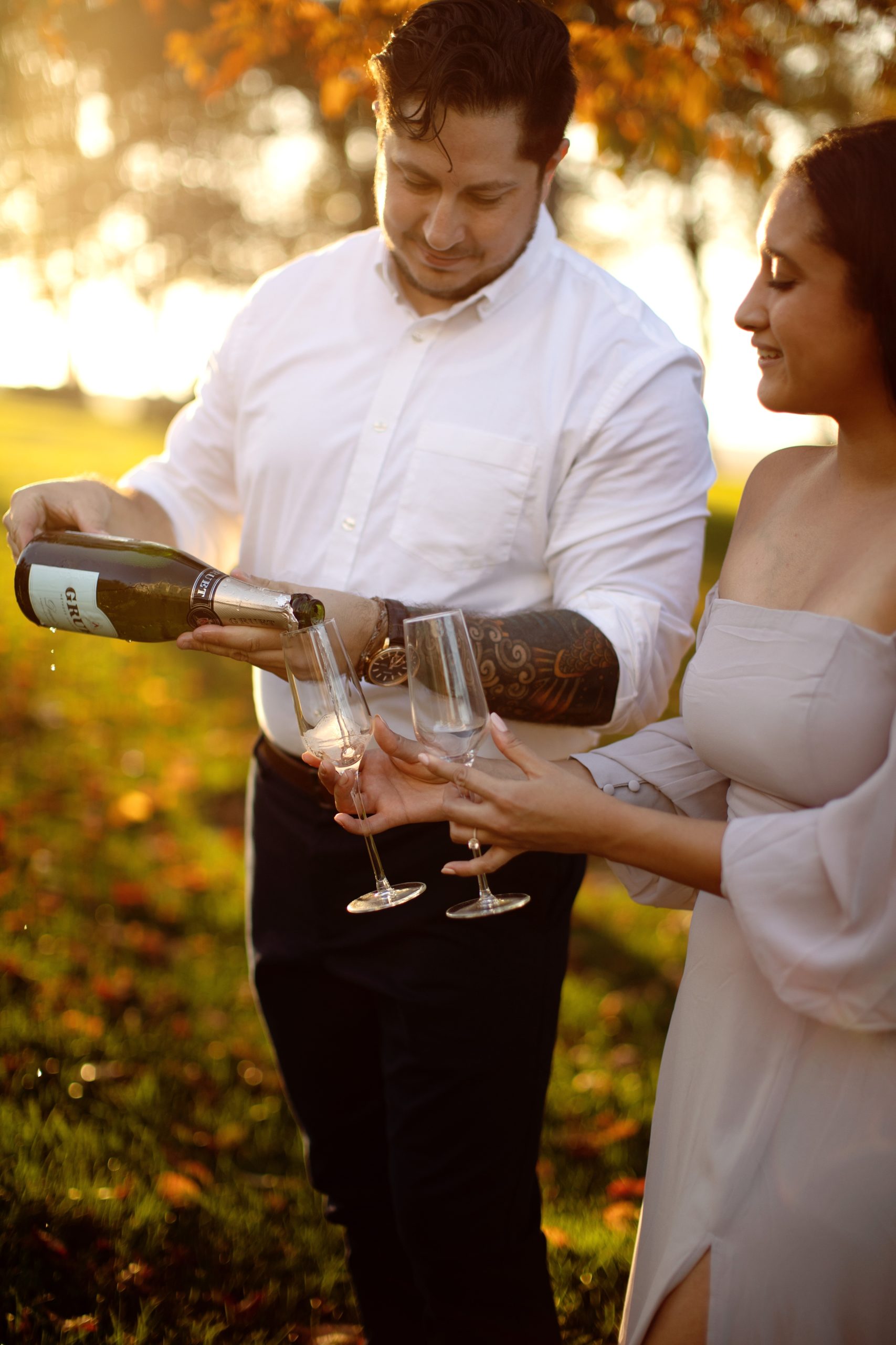 Engagement photo session at Drumore Estate in Lancaster PA. Bride is wearing a romantic off the shoulder lavender dress popping a bottle of champagne.