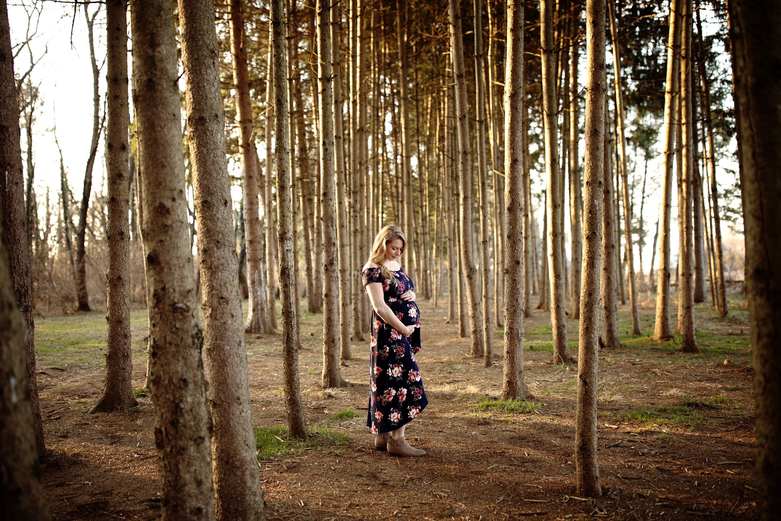 A winter maternity photo session at golden hour in Lancaster PA at Overlook Park. Tall Evergreen trees and warm tones captured by Lancaster Photographer Janae Rose Photography
